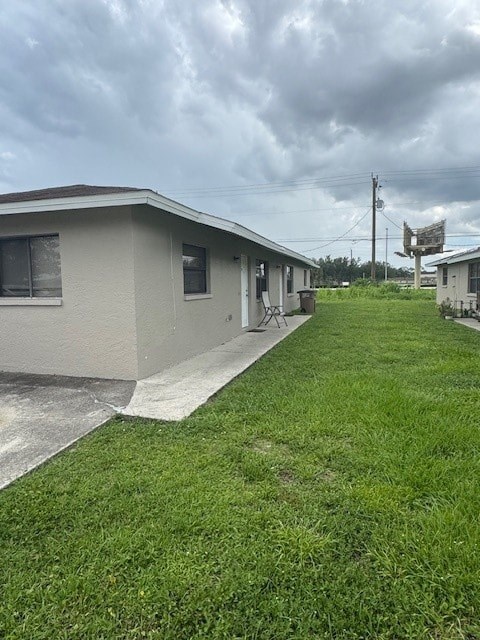 A grassy area in front of a building with a cloudy sky above.