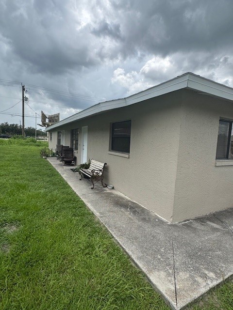 A small house with a grey roof and a concrete walkway in front.