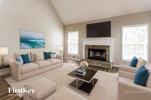 A living room with a fireplace and a painting of a beach scene on the wall.