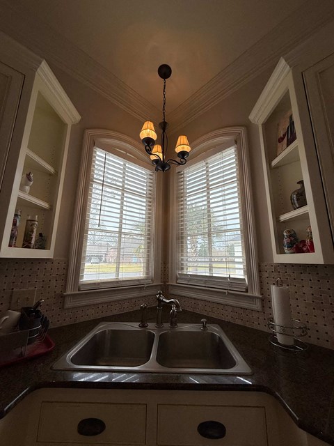 A kitchen with a sink and a window with blinds.