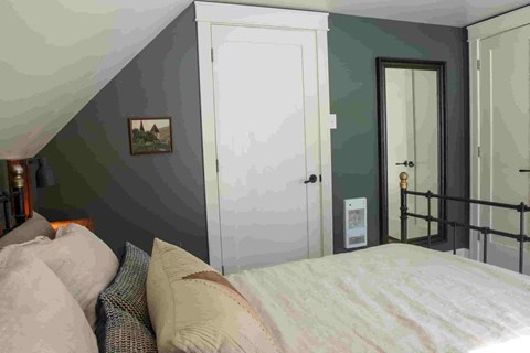 A bedroom with a bed and a painting on the wall.
