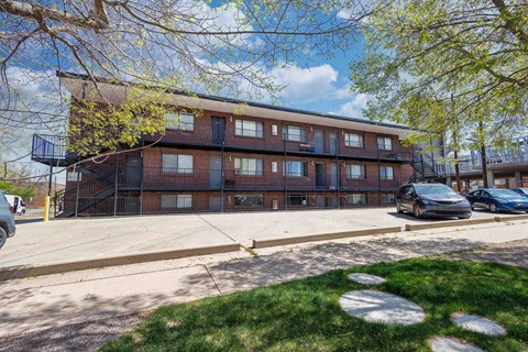 A brick apartment building with a parking lot in front.