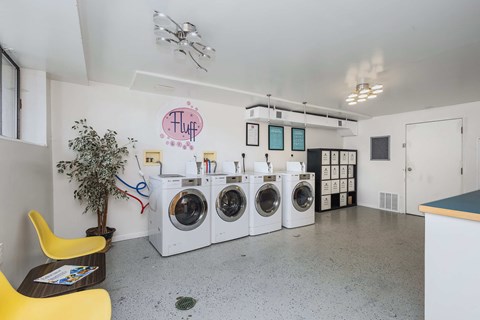 A laundry room with a row of washing machines and a yellow chair.