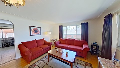 A living room with red couches and a chandelier.
