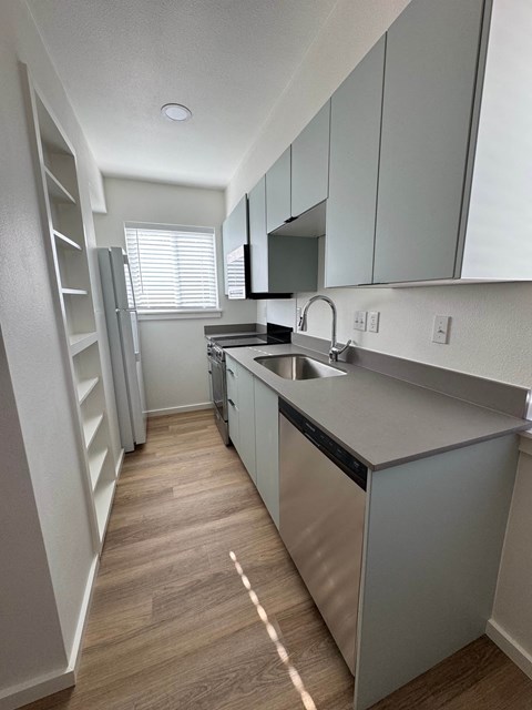A modern kitchen with a stainless steel dishwasher and wooden flooring.