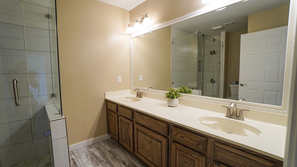 A bathroom with a white counter top and a mirror above it.