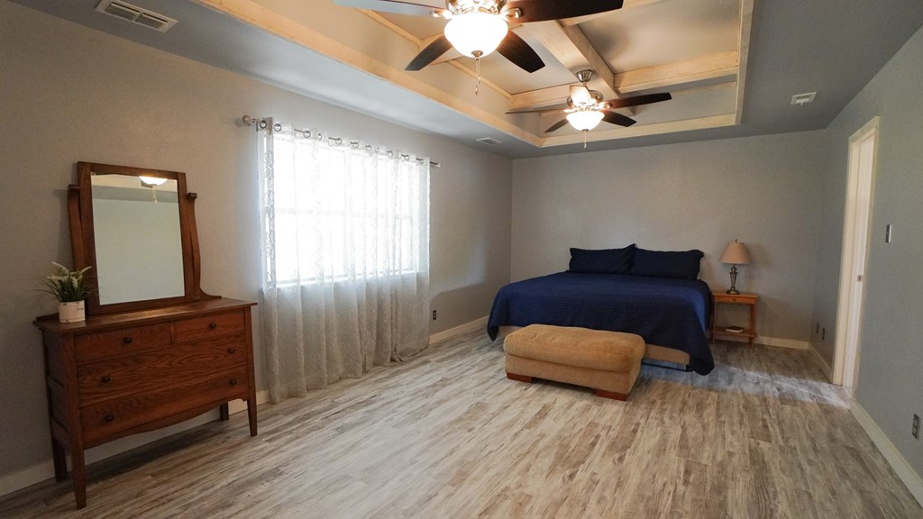 A bedroom with a bed, dresser, mirror, and window.