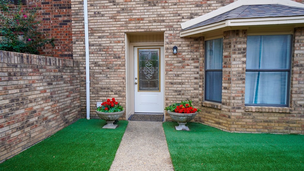 A house with a white door and windows with blue curtains.