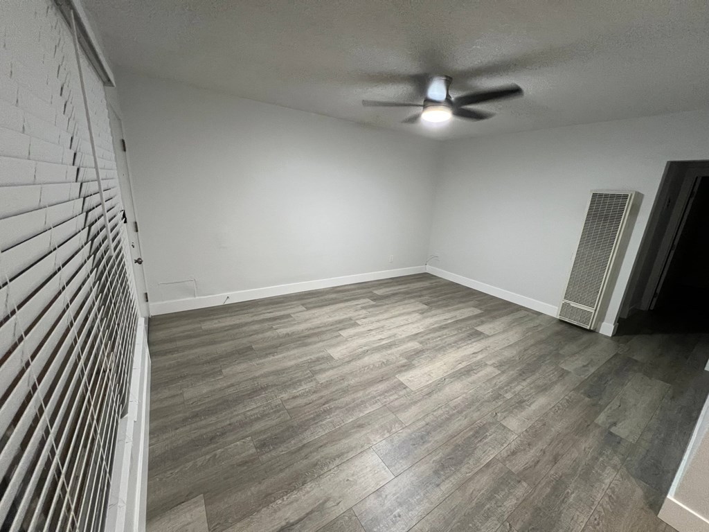 A room with a ceiling fan and wooden flooring.