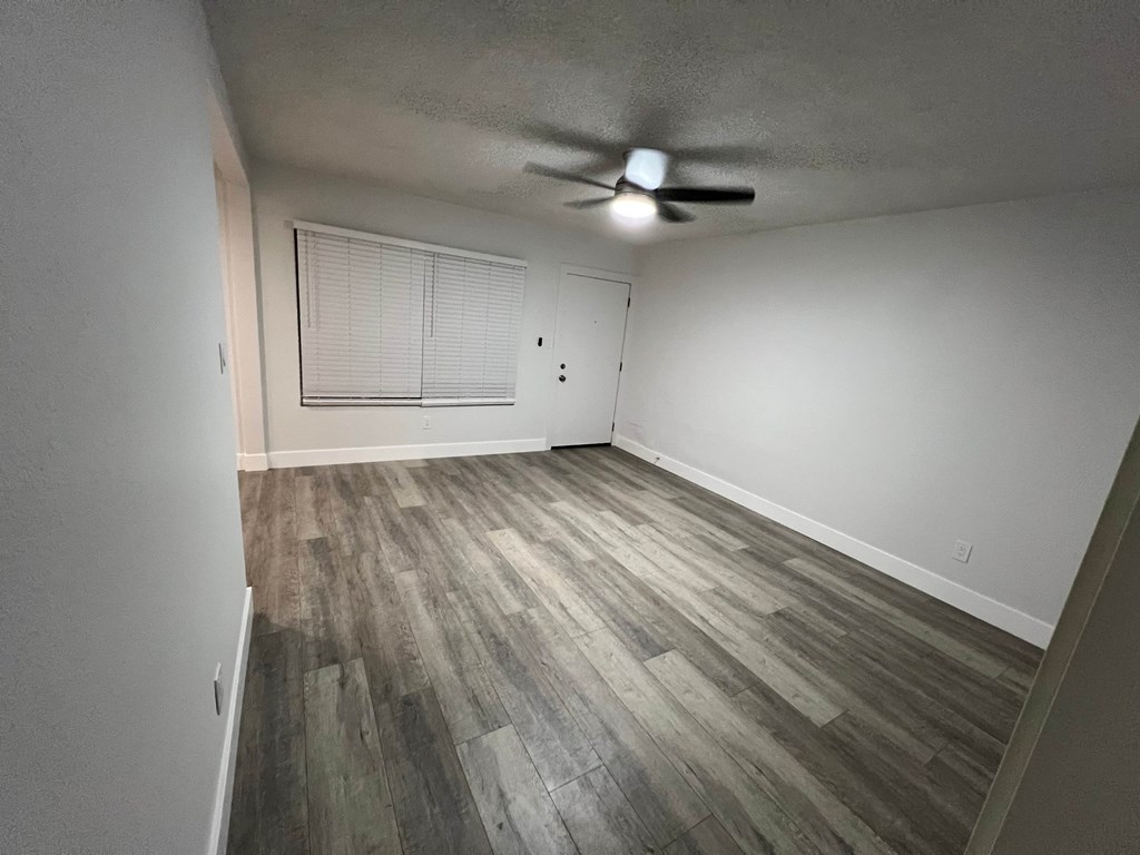 A room with a ceiling fan and wooden flooring.