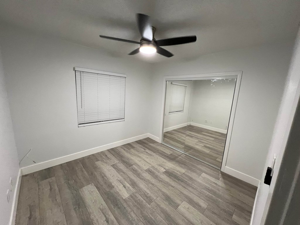 A room with a ceiling fan and a mirror on the wall.