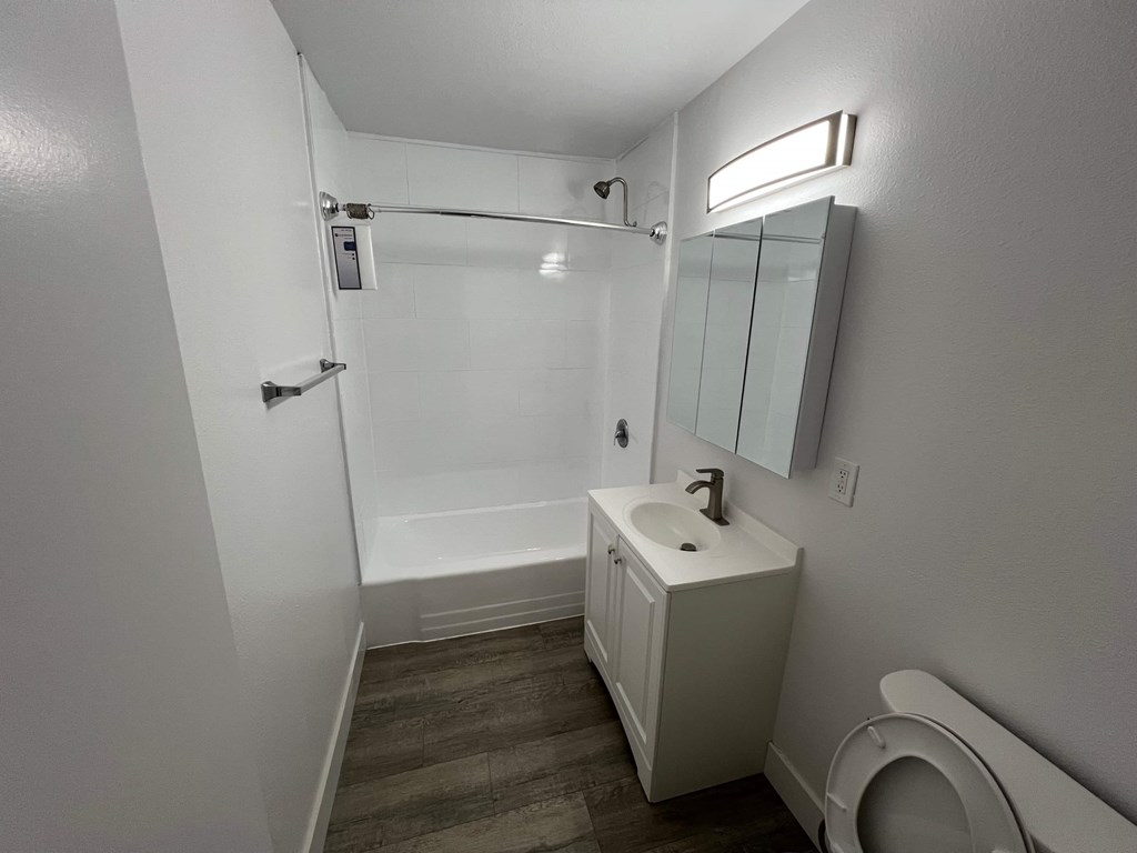 A white bathroom with a toilet, sink, and shower.