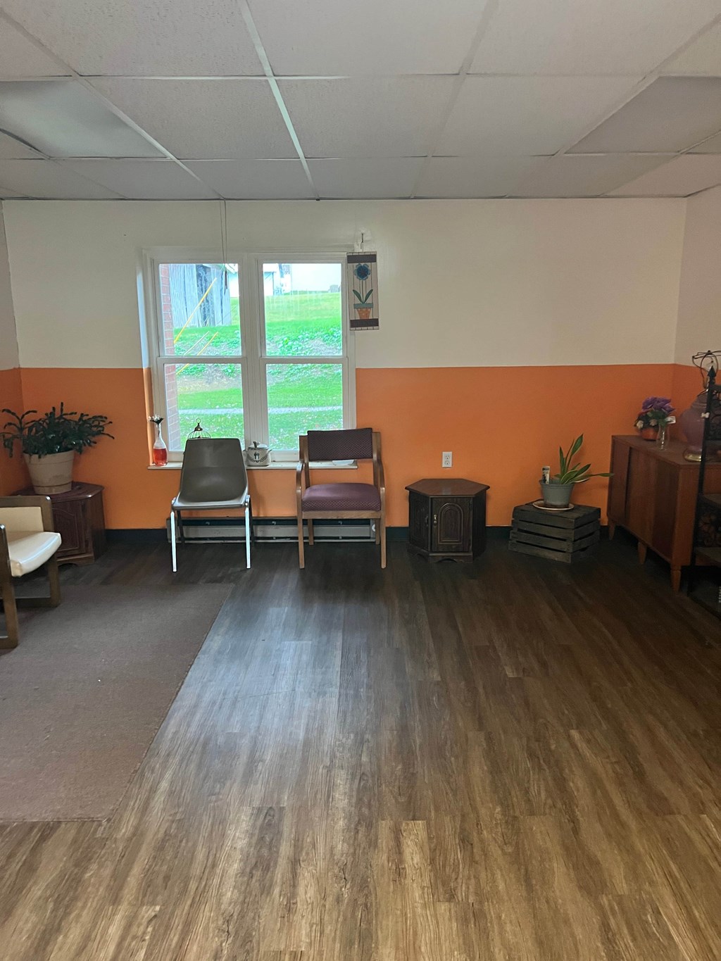 A room with orange walls and wooden floors has two chairs and a table.