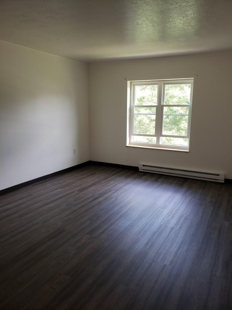 A room with a window and a radiator on the floor.