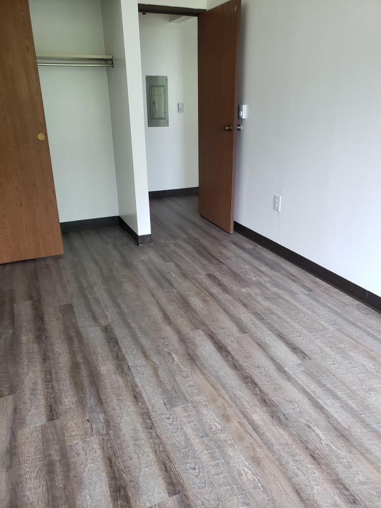 A hallway with wood flooring and two doors.