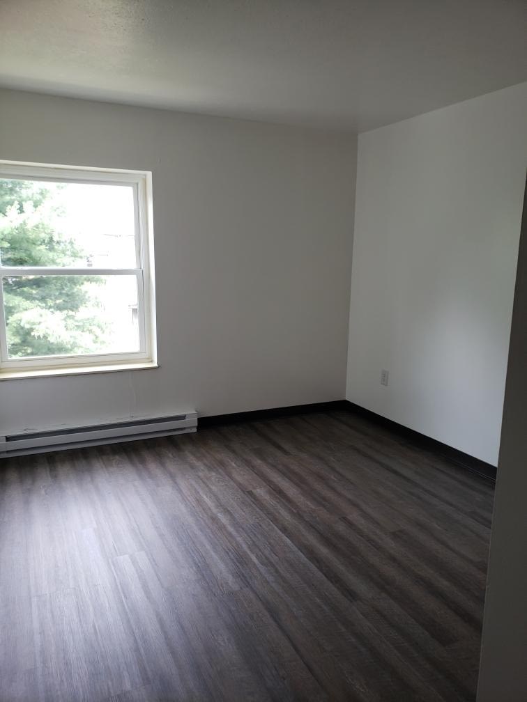 A room with a window and wood flooring.
