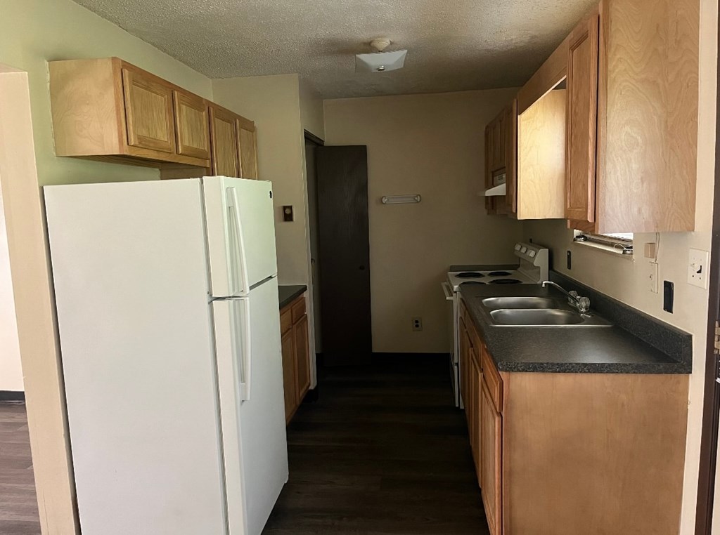 A kitchen with a white fridge and wooden cabinets.