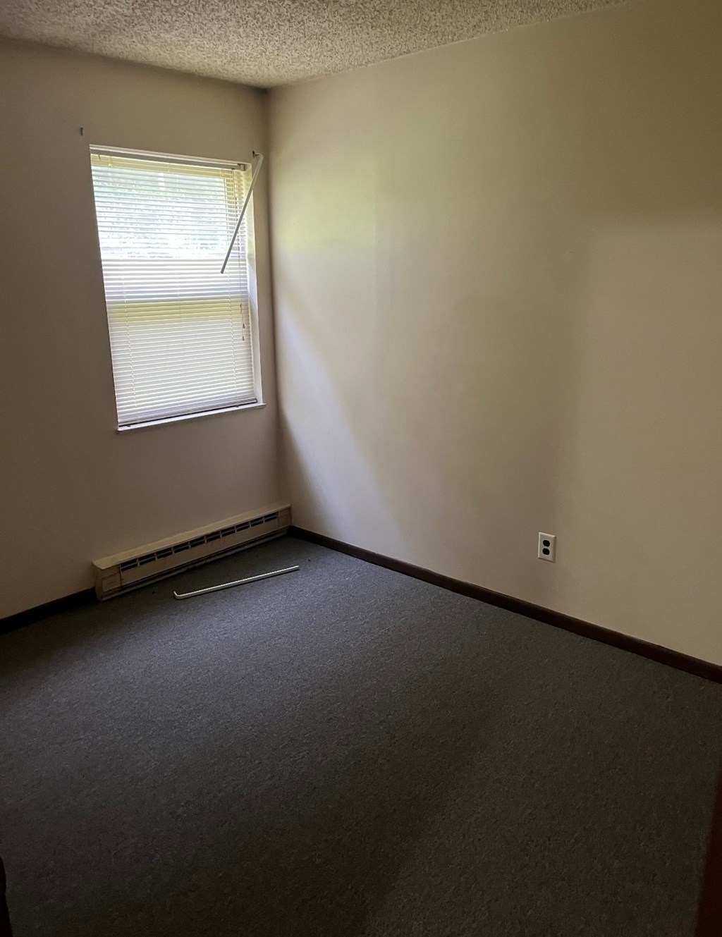 A room with a window and a heater on the floor.