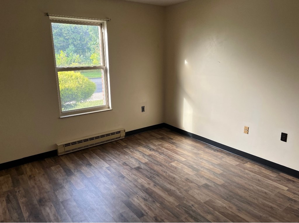 A room with a window and a wooden floor.