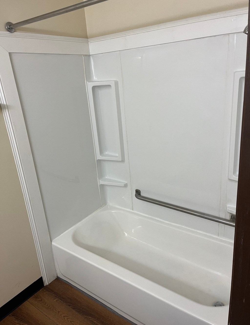 A white bathtub with a shower head and a door.