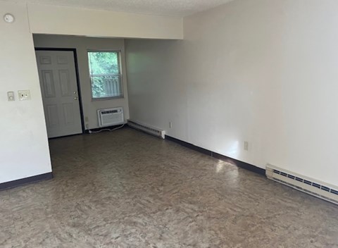 A room with a door and a window with a white wall and a carpet.