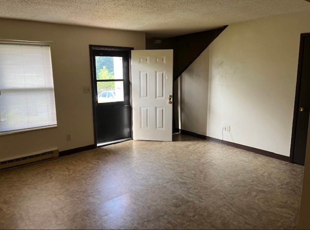 A room with a black door, a white door, and a window with blinds.