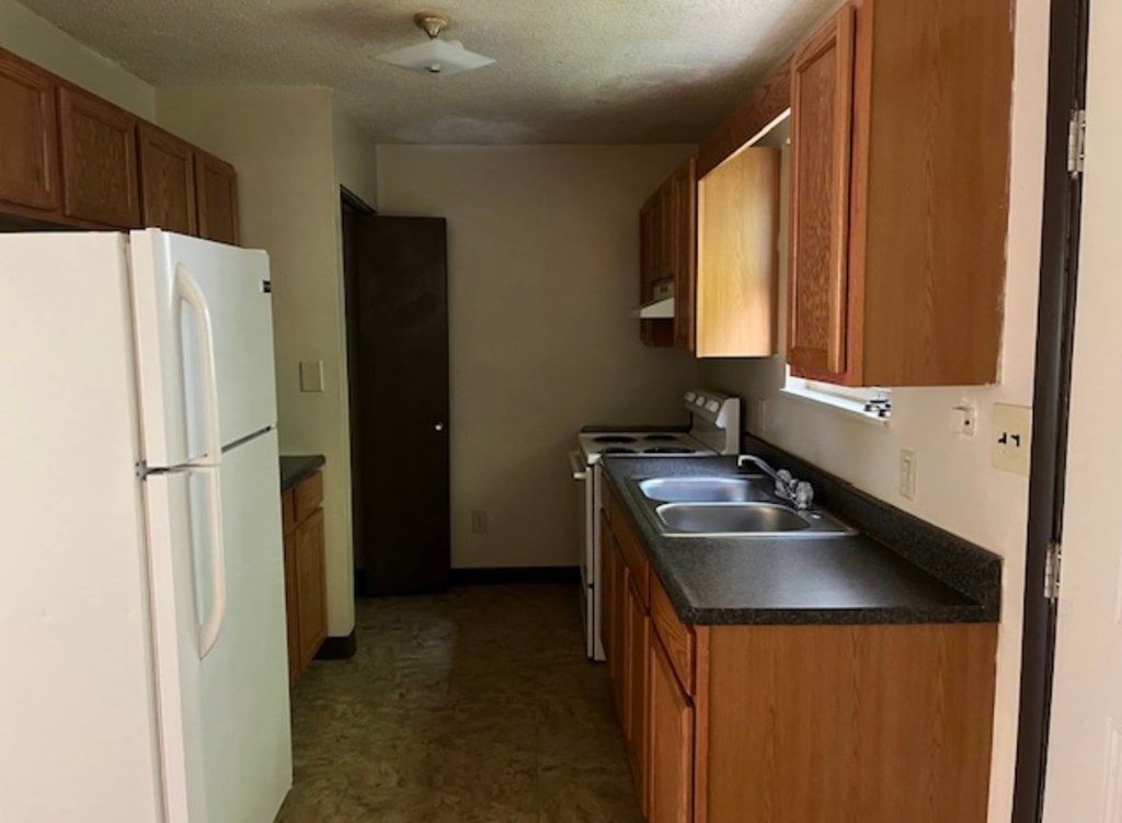 A kitchen with a white fridge and wooden cabinets.