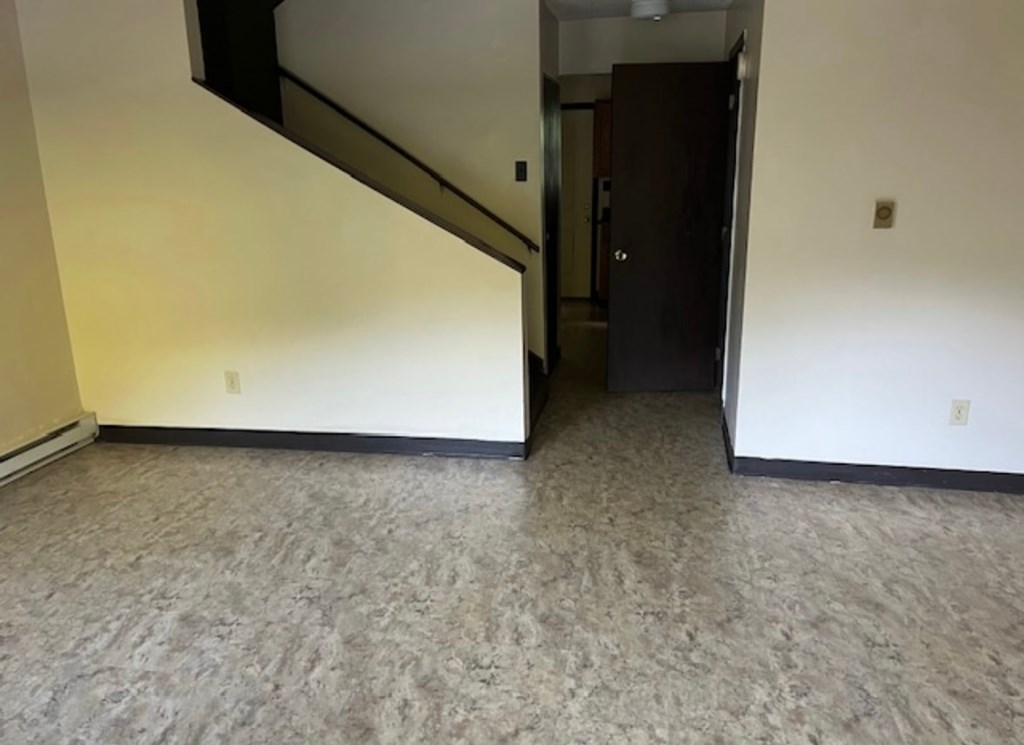 A room with a carpeted floor and a staircase.