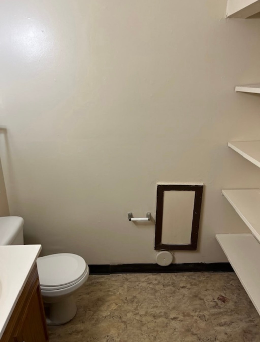 A bathroom with a toilet, sink, and a mirror.