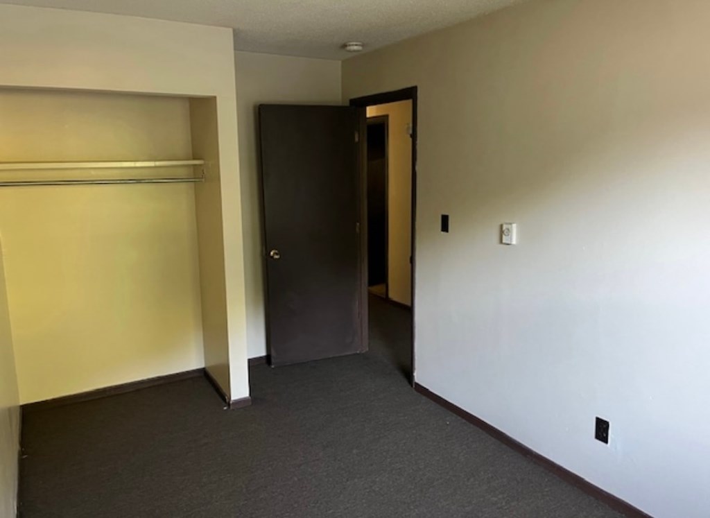 A room with a black door and a white wall.