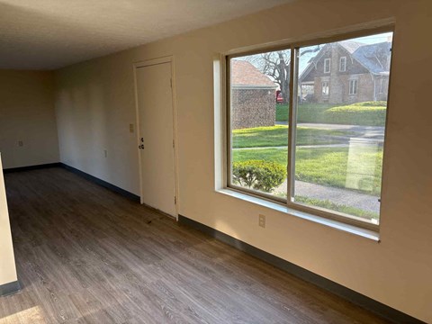 A room with a large window and a wooden floor.