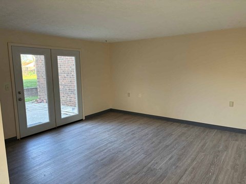 A room with a sliding glass door and wood flooring.