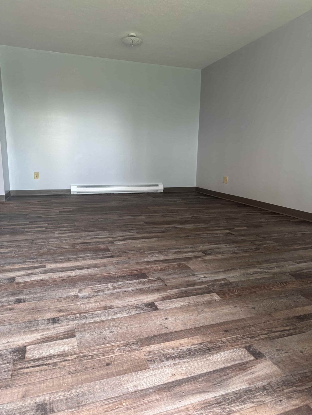 A room with wooden flooring and a white wall.
