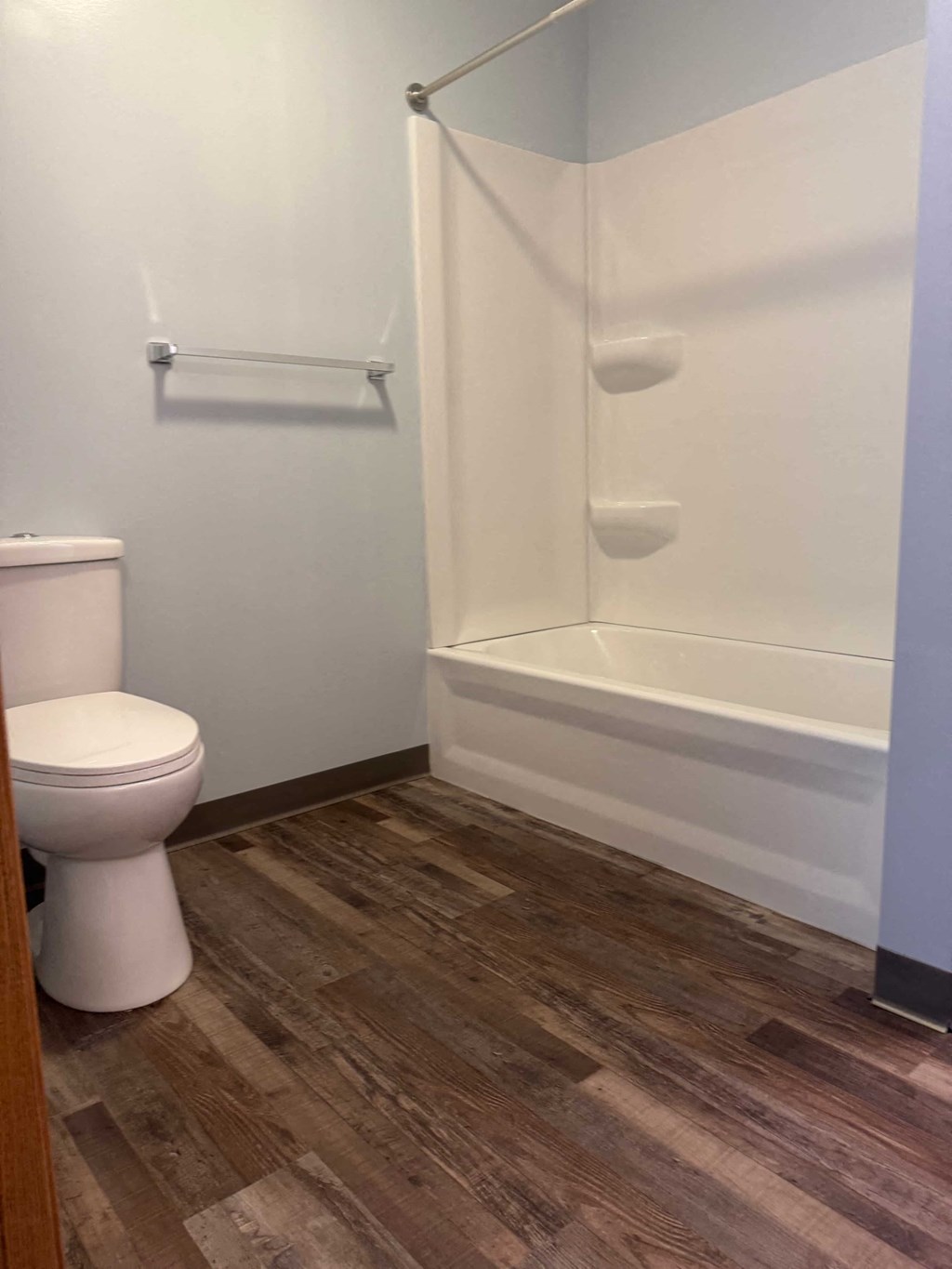 A white toilet sits next to a white bathtub in a bathroom.