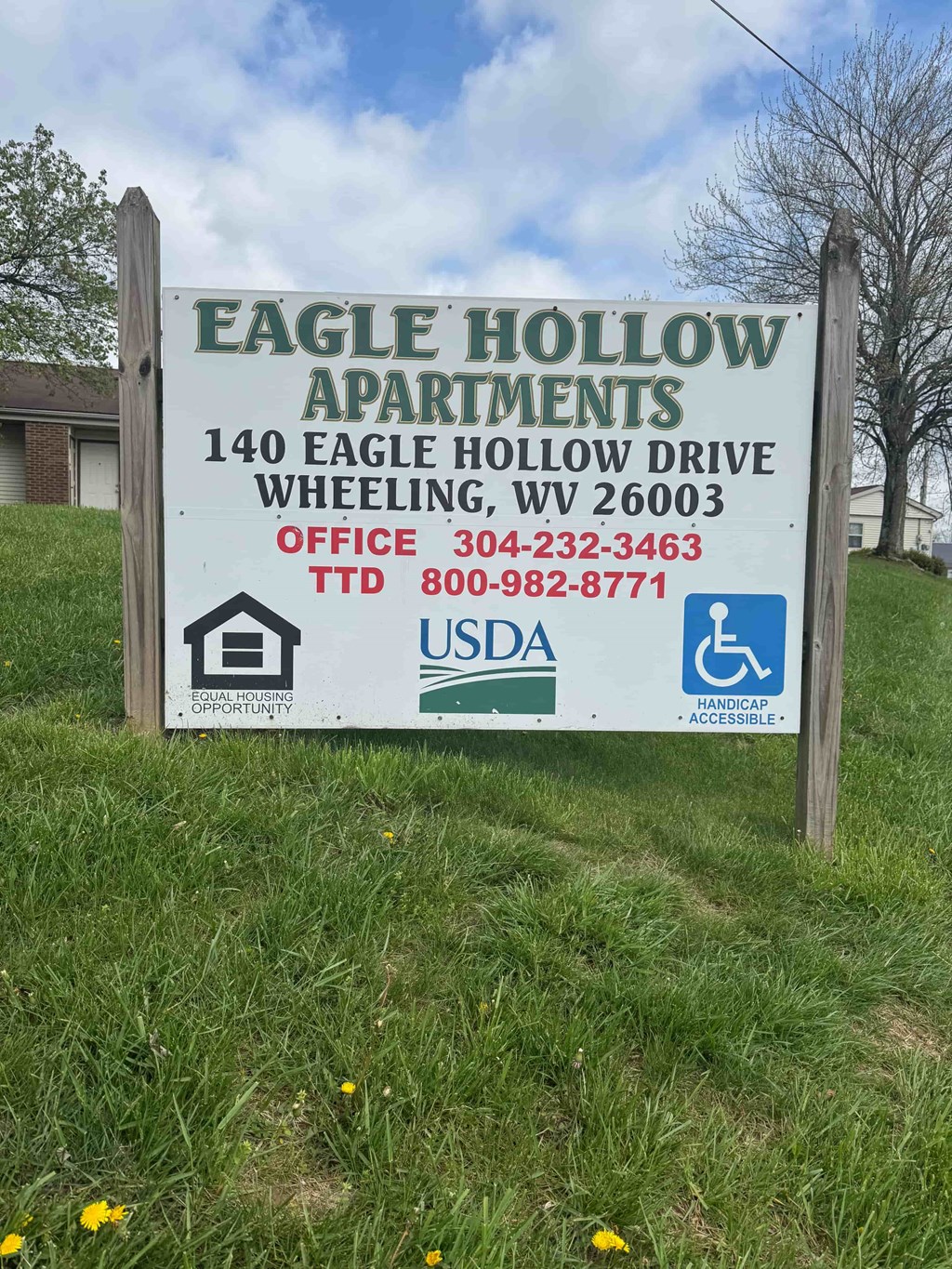 A sign for Eagle Hollow Apartments is displayed in a grassy area.
