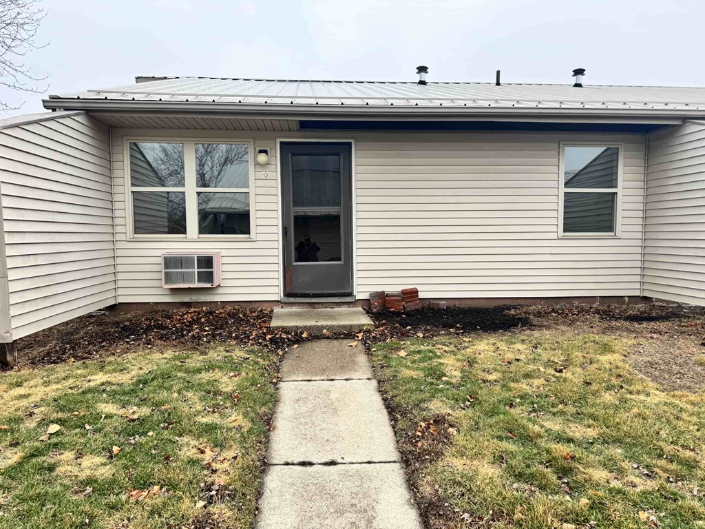 A small house with a grey siding and a black door.