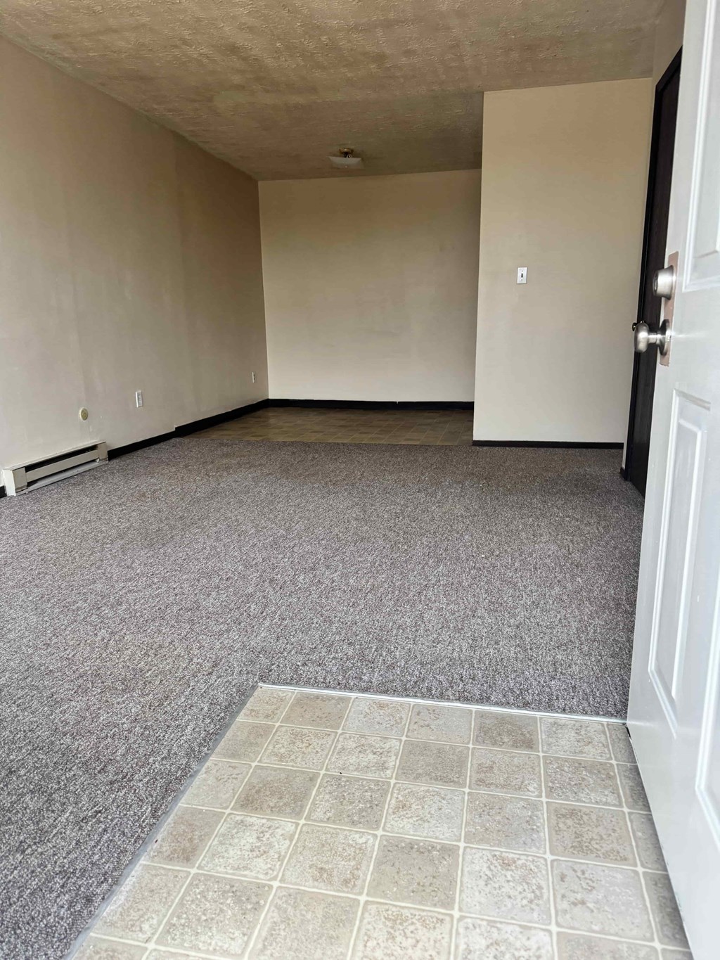 A room with a carpeted floor and a door on the right side.
