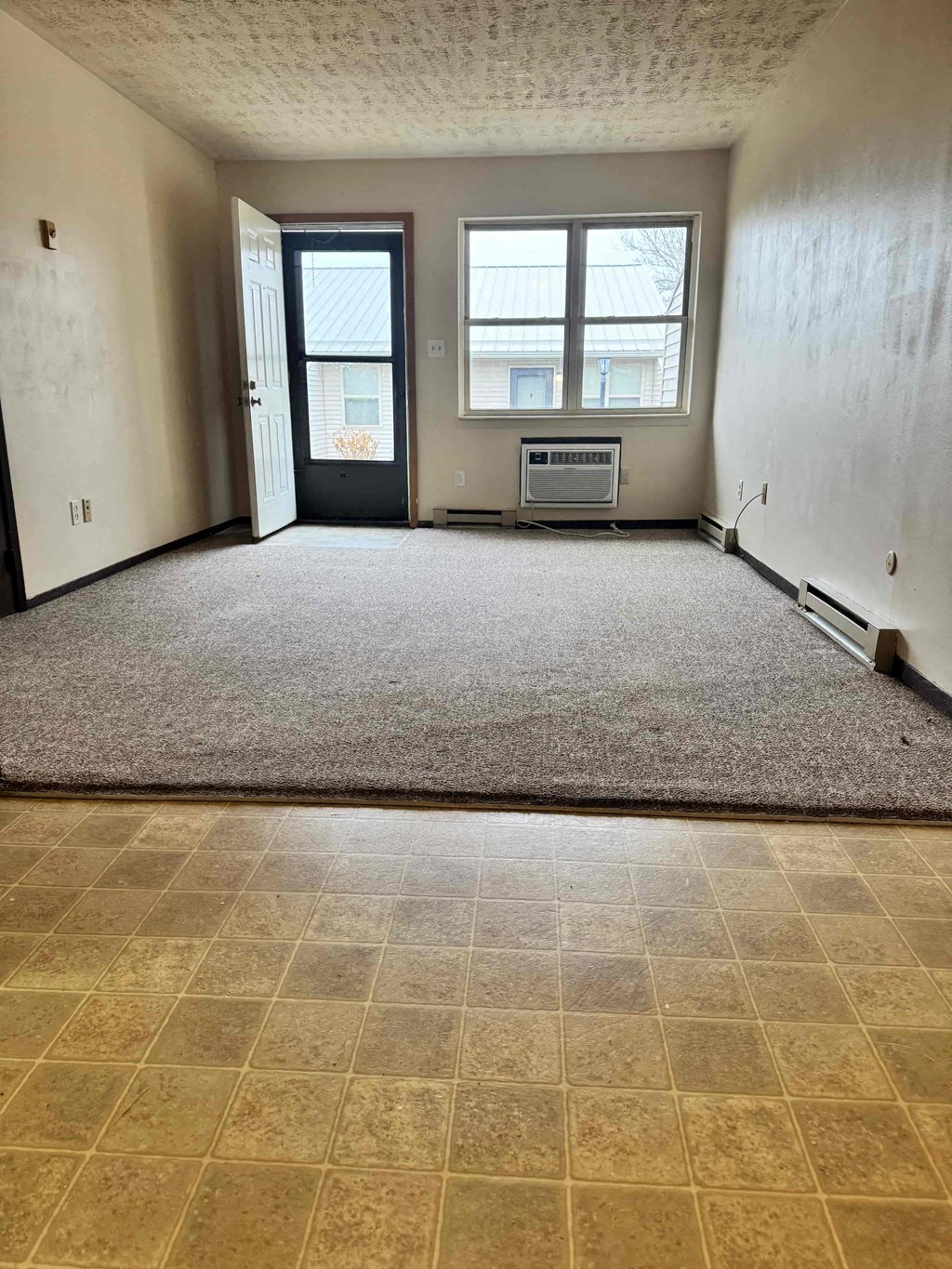 A room with a carpeted floor and a window.