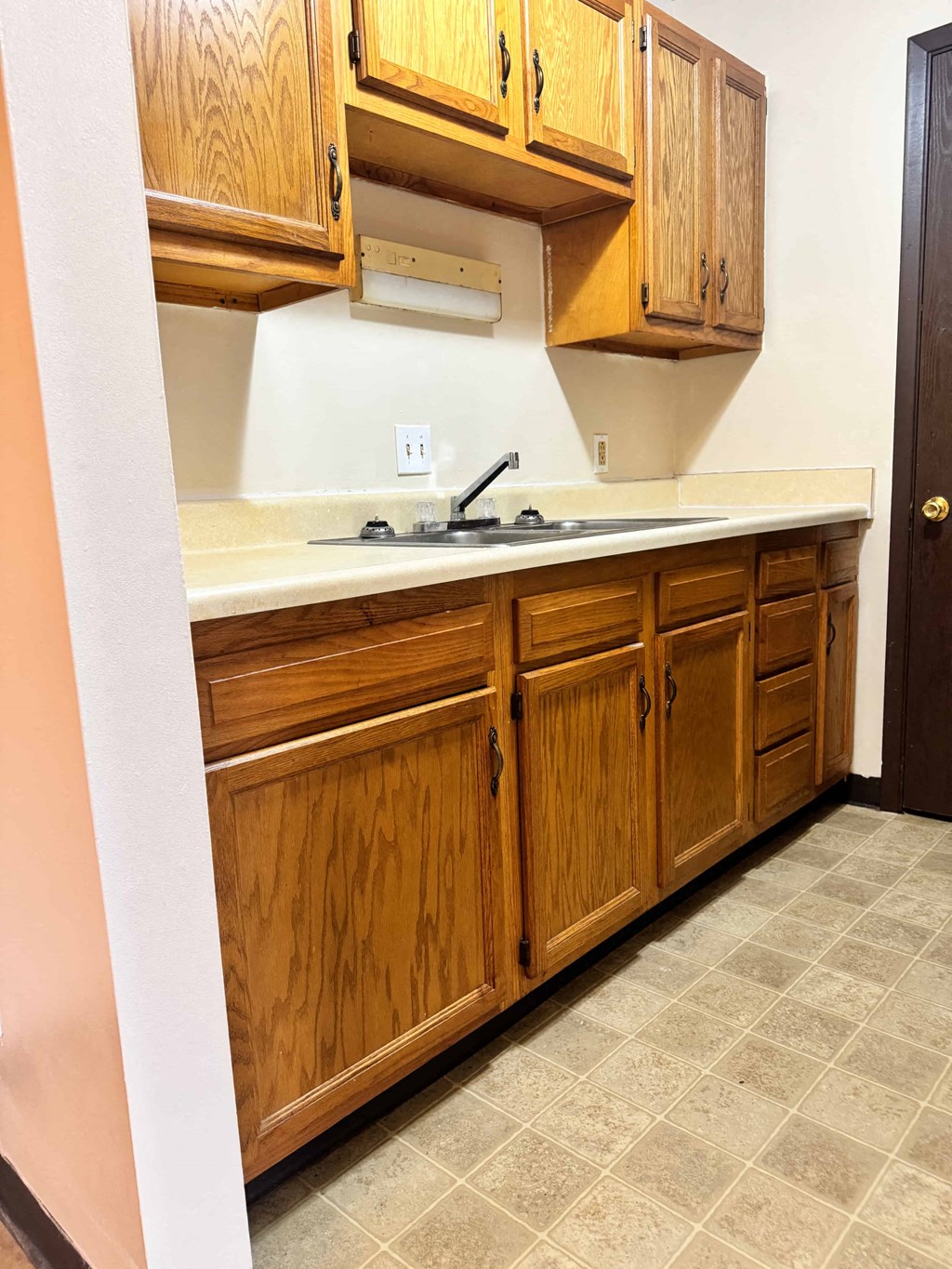 A kitchen with wooden cabinets and a tile floor.