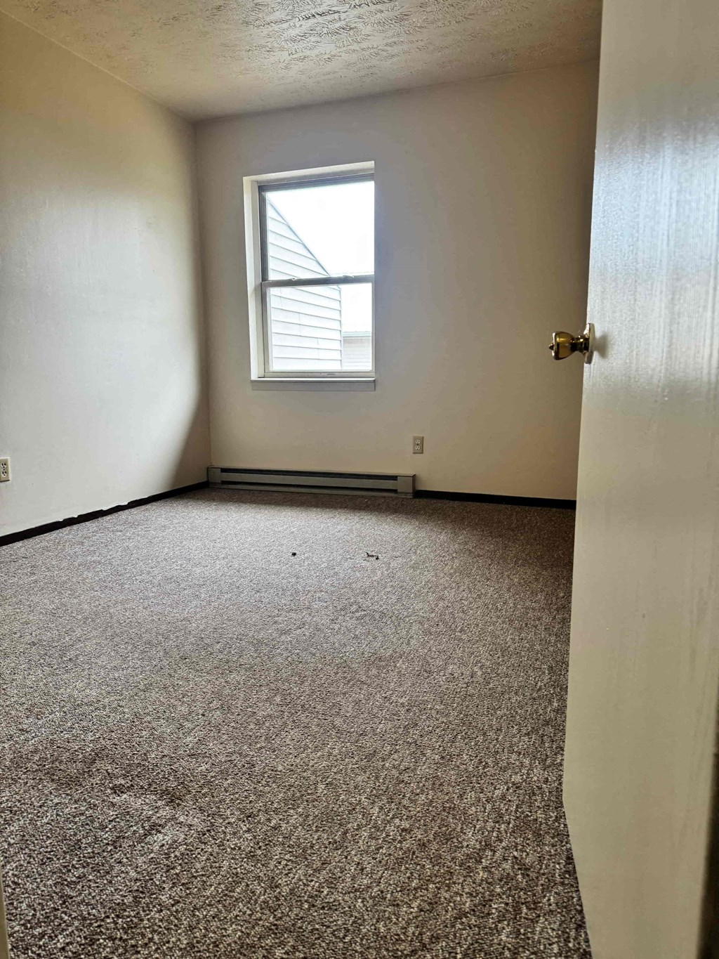 A room with a carpeted floor and a window.