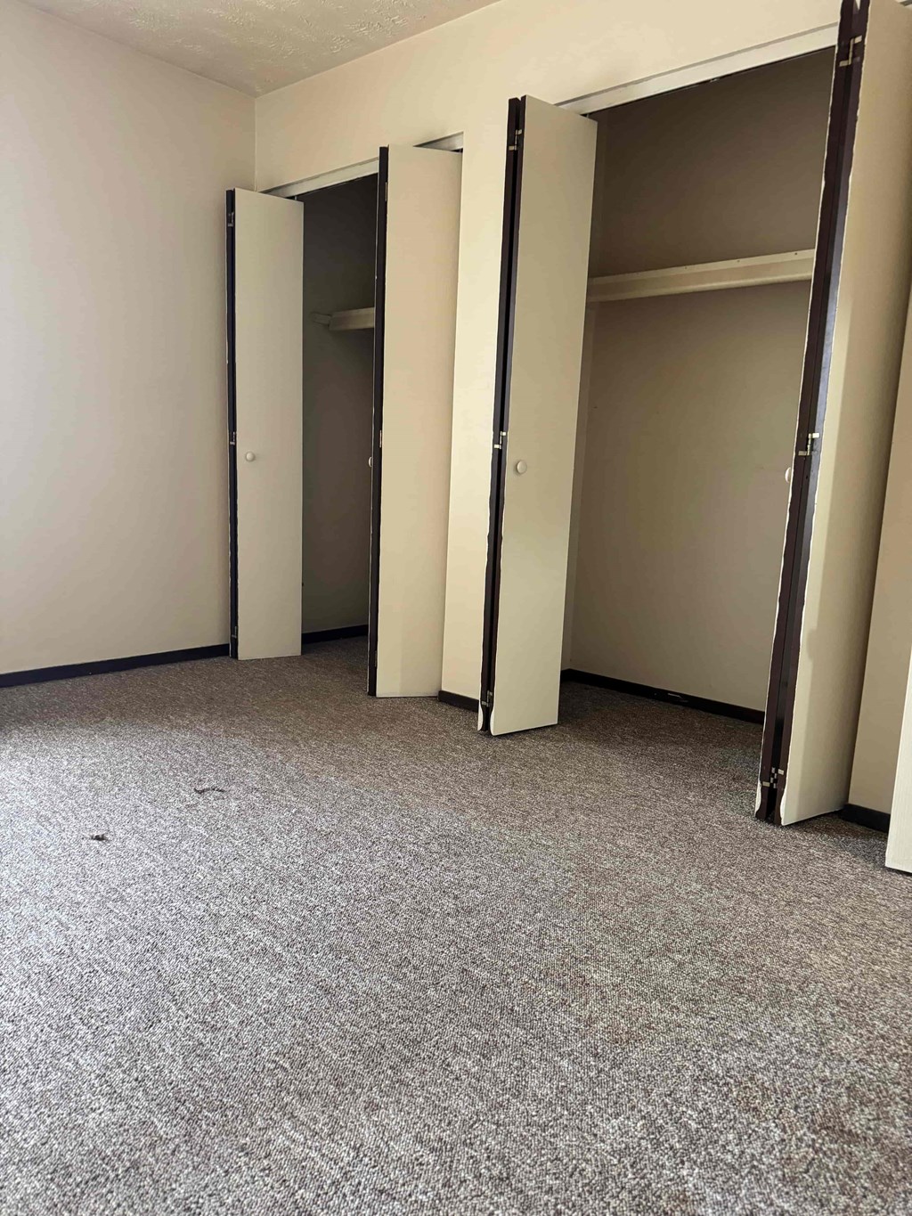 A room with a carpeted floor and three open doors.