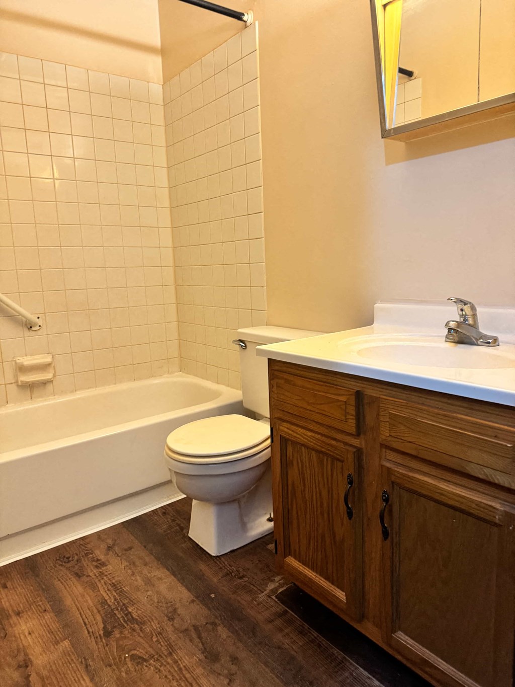 A white toilet sits in a bathroom next to a white bathtub.