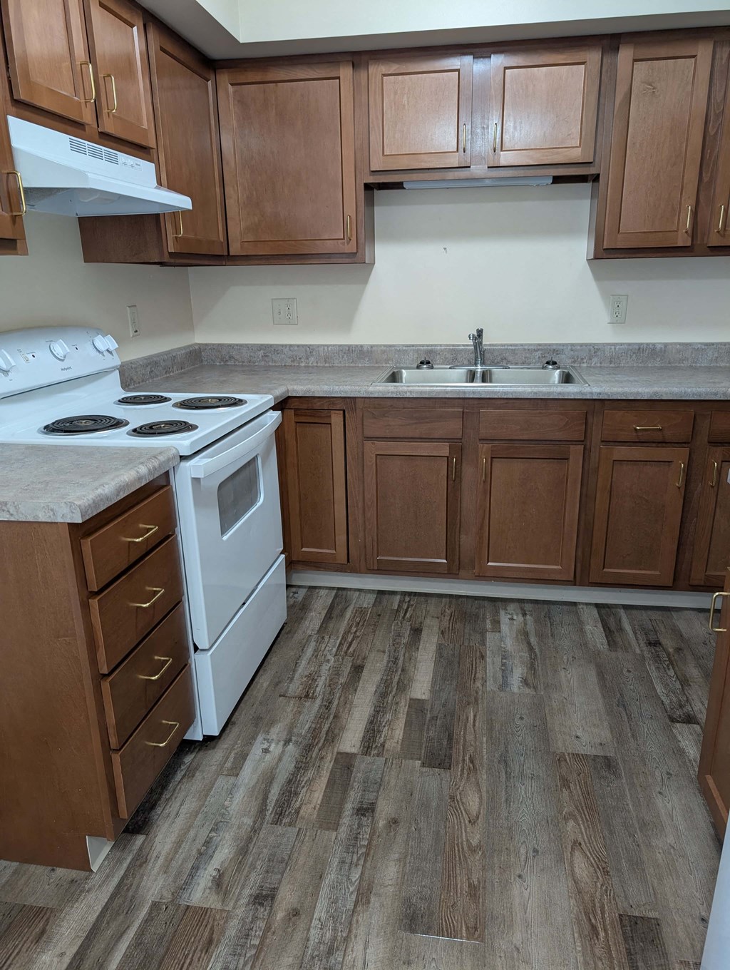 A kitchen with wooden cabinets and a white stove top oven.