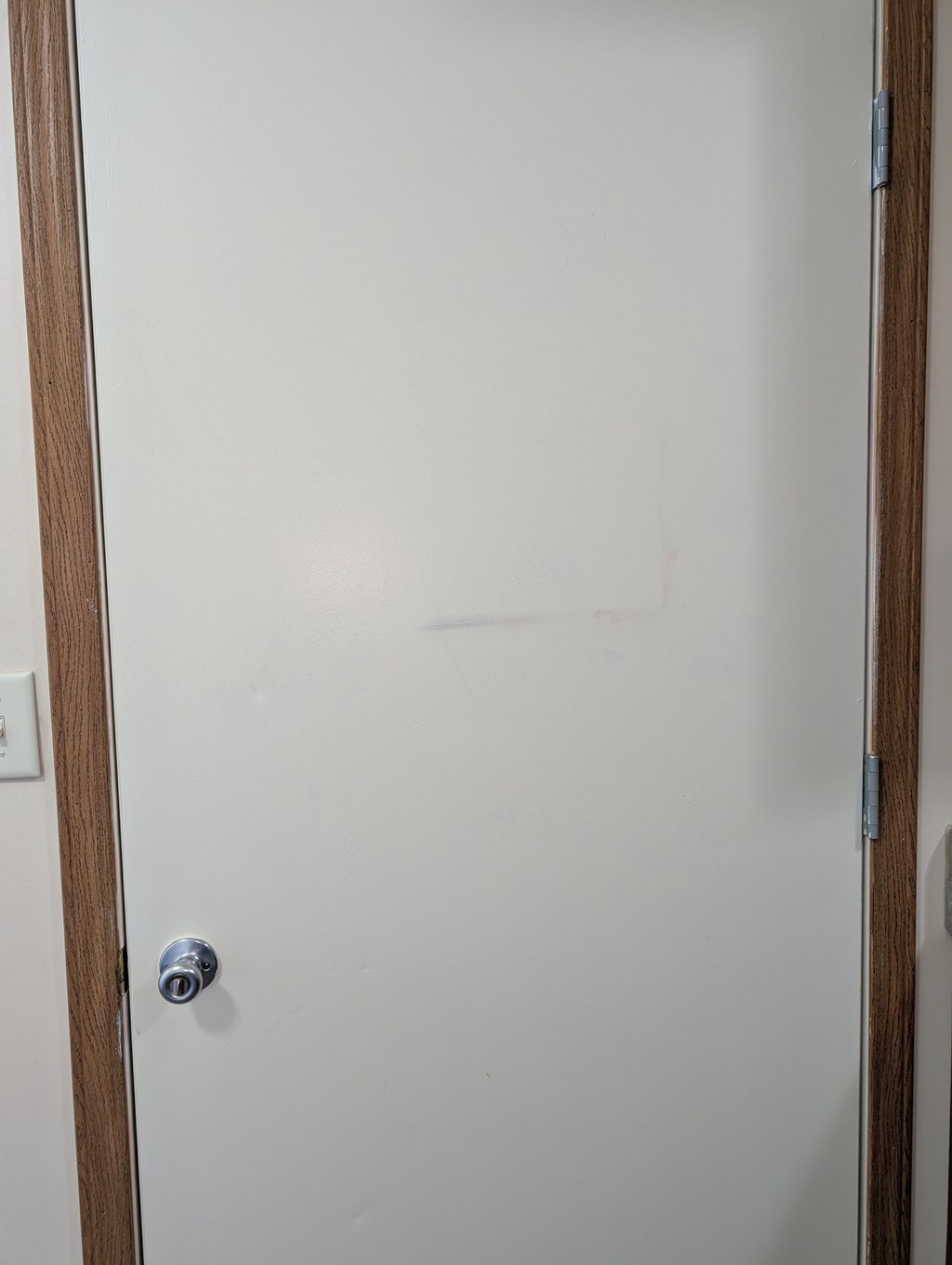 A white door with a silver handle and a small square sticker on the right side.