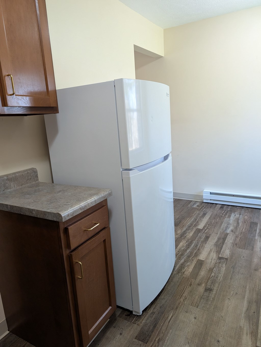 A white refrigerator in a kitchen with wooden cabinets.