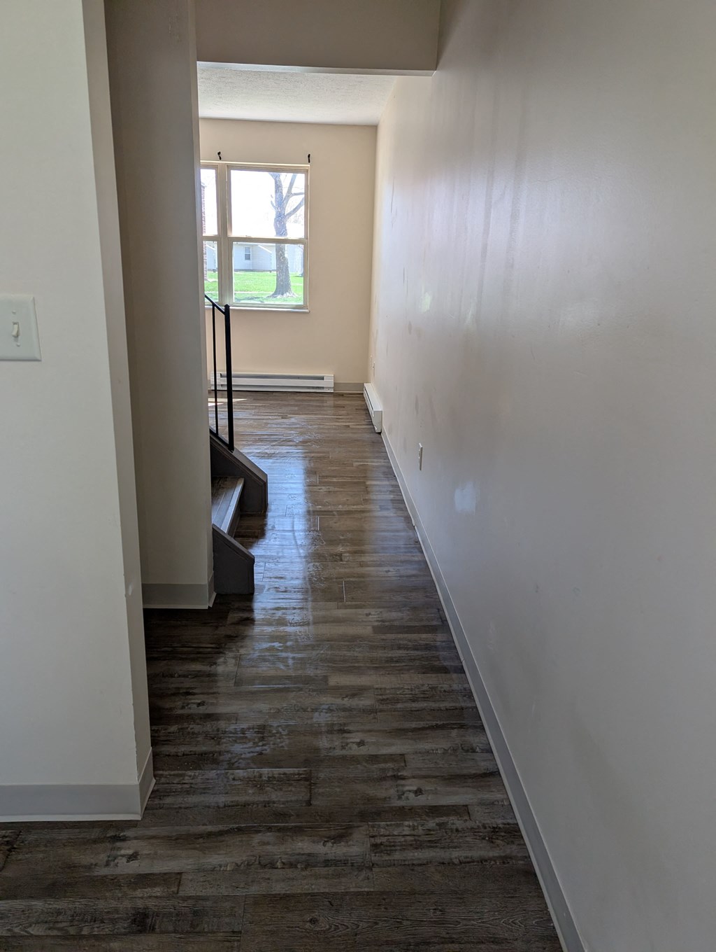 A long hallway with a wooden floor and white walls.