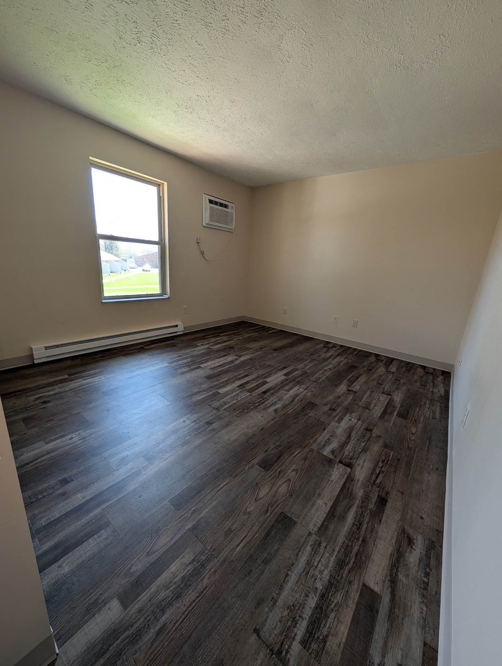 A room with wooden flooring and a window.