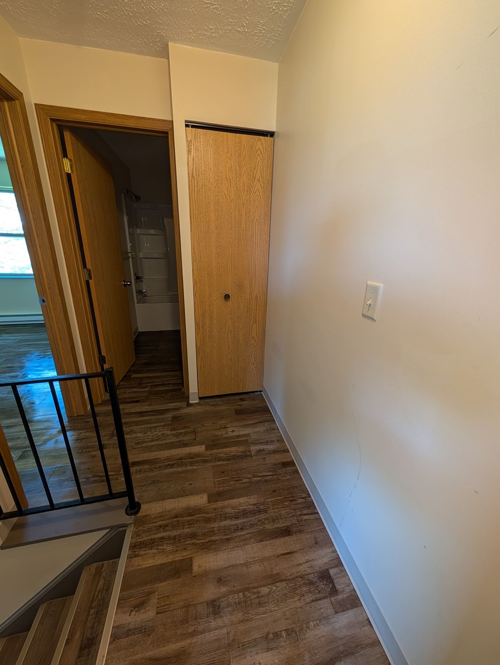 A hallway with a wooden door and a black railing.