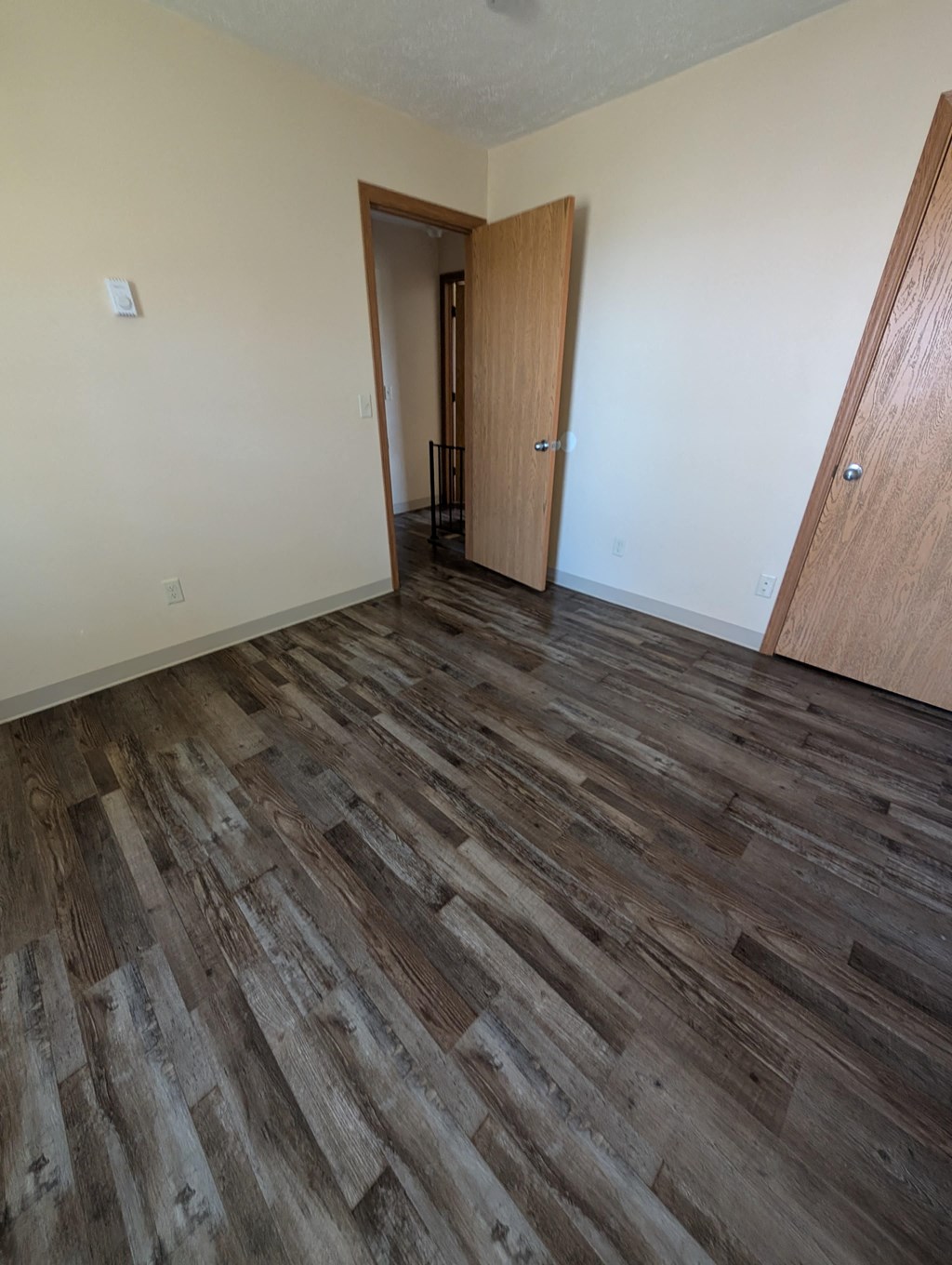 A room with wood flooring and a doorway leading to another room.
