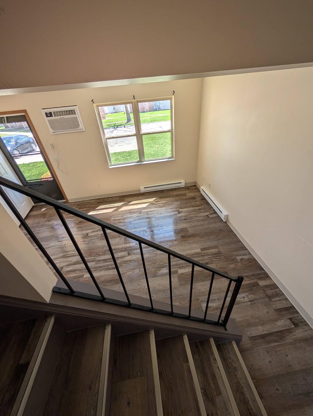 A room with a window and a staircase leading to the second floor.